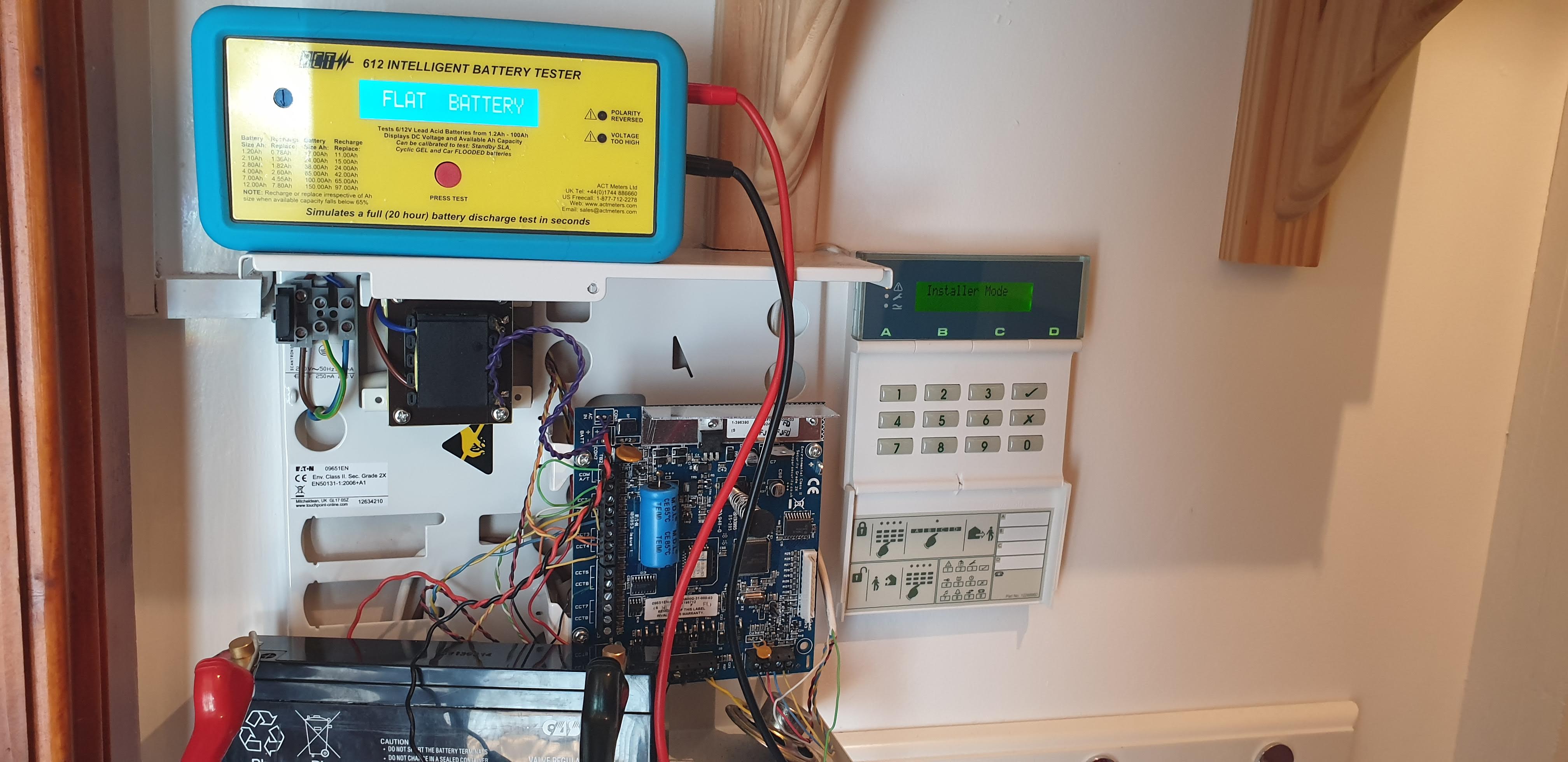 Technician performing maintenance on an intruder alarm system